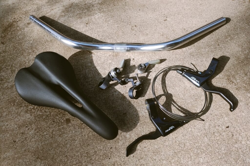 Bike parts including silver handlebars, bike saddle, thumbies, friction shifters, and brake levers.
