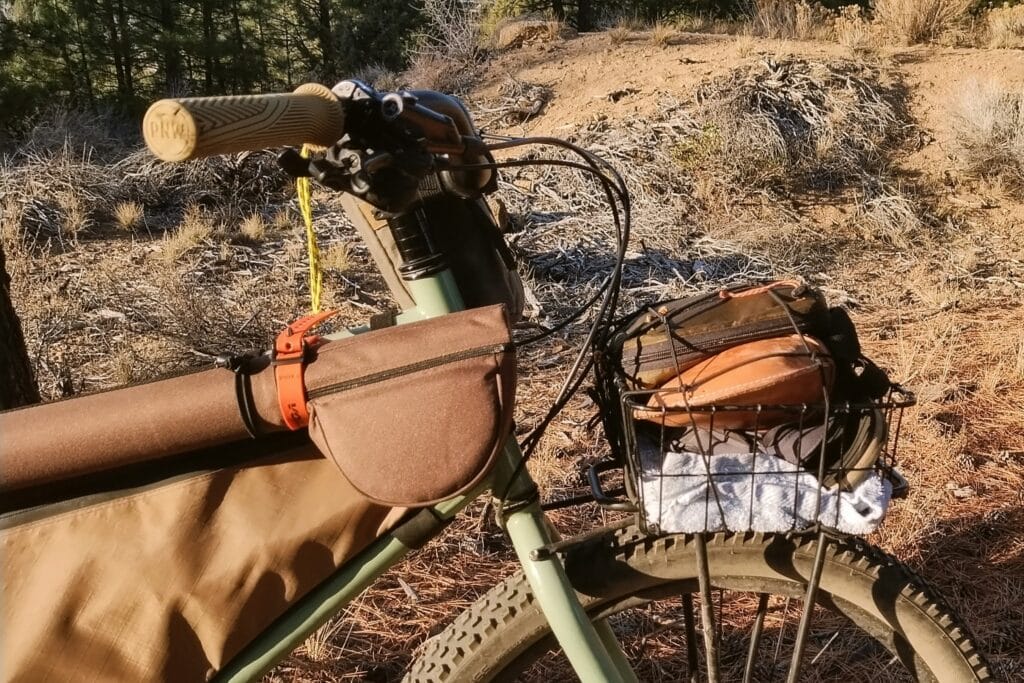 Fishing rod strapped to a Surly Grappler top tube and fishing gear packed in a front basket.