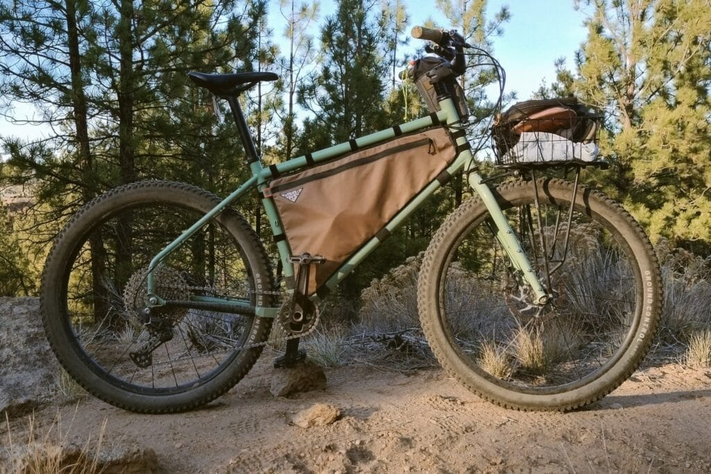 Profile view of a Surly Grappler with a tan frame bag and front basket rack.