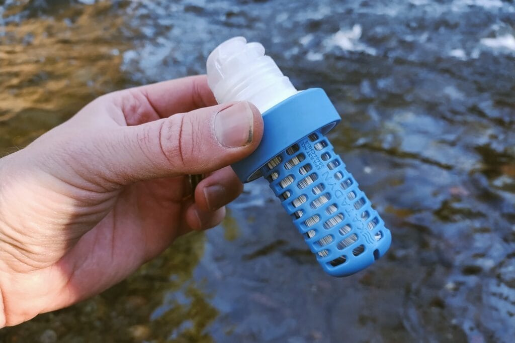 Katadyn BeFree Water Filtration System 1.0L fiber filter held in front of a creek.