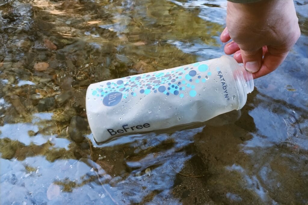 Katadyn BeFree Water Filtration System 1.0L bladder being filled in a creek.