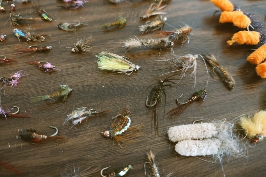 Various colorful fly fishing flies laid out on a table.