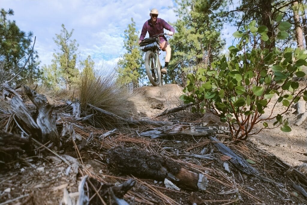 A man riding a bike down a rocky trail with manazita off to the side.