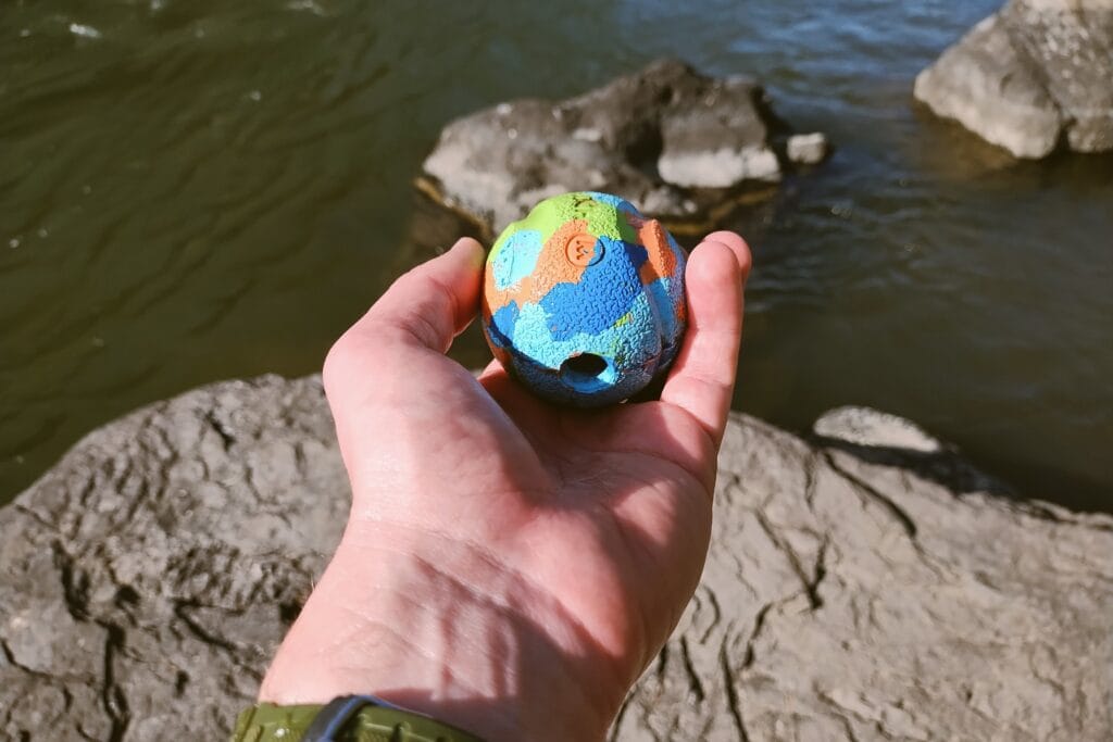 A blue, orange, and green dog toy ball found in a river.