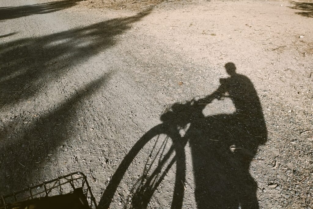 Shadow of a man riding his bike on dirt.